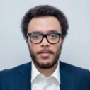 Diego-Rivera-Headshot-Wearing a Blue Suit, White Shirt, Transparent Frame Glasses