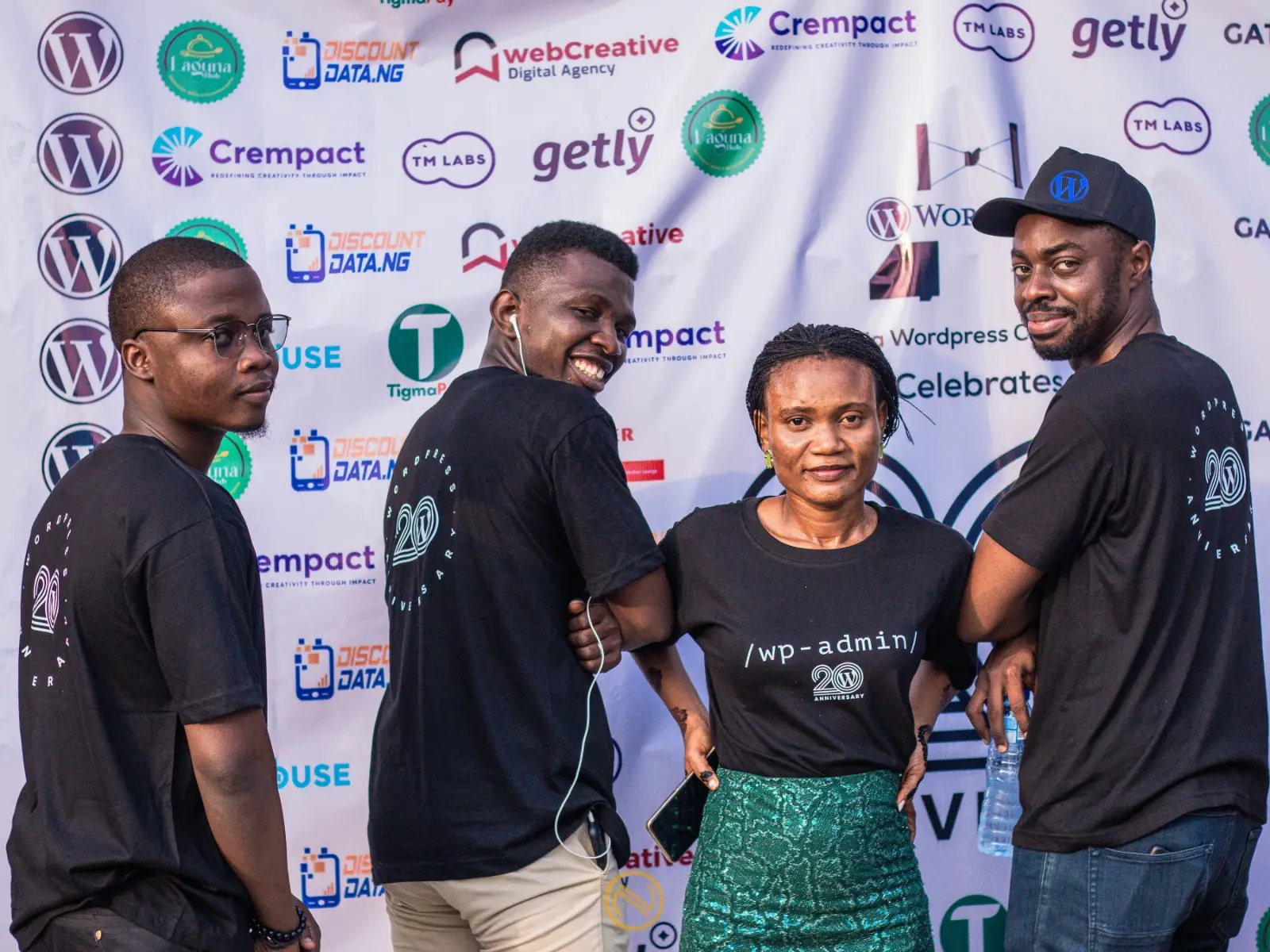 WordPress community members wearing anniversary t-shirts and posing during a WordPress celebration event.